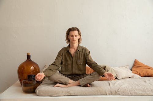 Free Serene man meditating in Lotus Pose on sofa Stock Photo